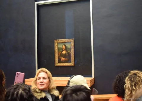 Visitatori davanti alla Monna Lisa dietro il vetro sulla parete scura, momento clou con biglietti Museo del Louvre
