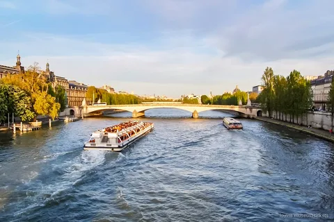 Bateau de croisière sur la Seine passant devant des monuments parisiens, inclus dans le combiné du musée du Louvre
