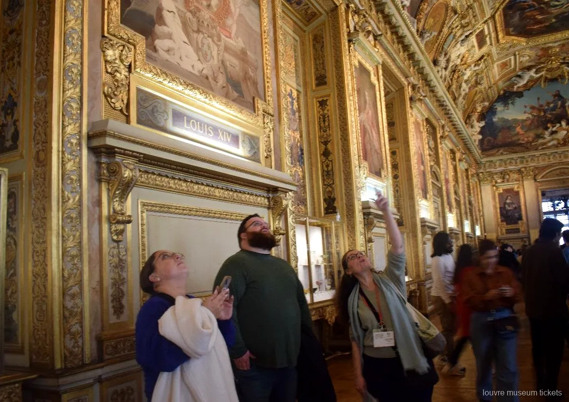 Kleine groep kijkt omhoog naar het beschilderde, vergulde plafond van de Galerie d'Apollon, met Louvre museum tickets