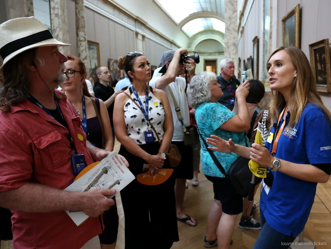 Gids in blauw shirt spreekt een groep met Louvre plattegronden toe in een galerij, met Louvre museum tickets