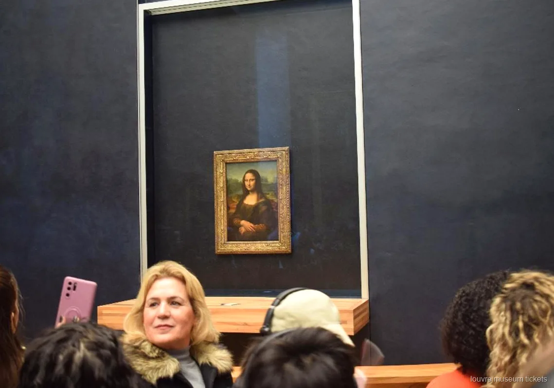 Salonun koyu duvarında cam arkasındaki Mona Lisa önünde ziyaretçiler, Louvre Müzesi biletleri ile turun öne çıkan anı