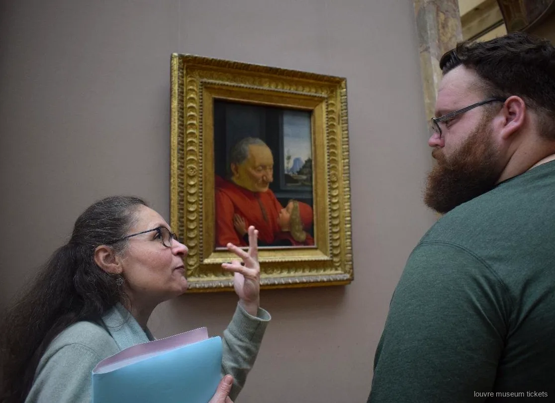 Guia explicant a un visitant un retrat renaixentista d'un ancià amb un nen, amb entrades del Museu del Louvre