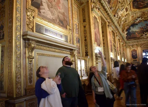 Grupo reducido mirando el techo pintado y dorado de la Galería de Apolo, visita con entradas Museo del Louvre