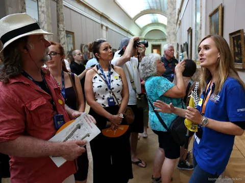 Guia de samarreta blava amb un grup que porta plànols del Louvre, visita guiada amb entrades del Museu del Louvre