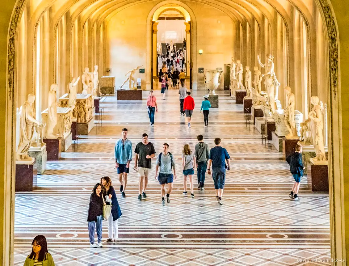 Visiteurs dans une galerie de sculptures antiques aux arches et sol de marbre, visite avec billets musée du Louvre